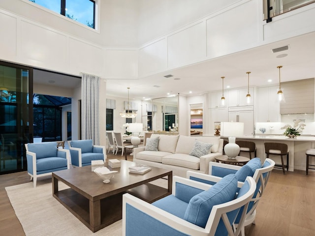 living room featuring a towering ceiling and light hardwood / wood-style flooring