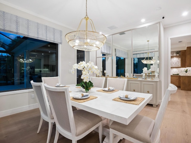 dining area featuring light wood-type flooring, crown molding, and a notable chandelier