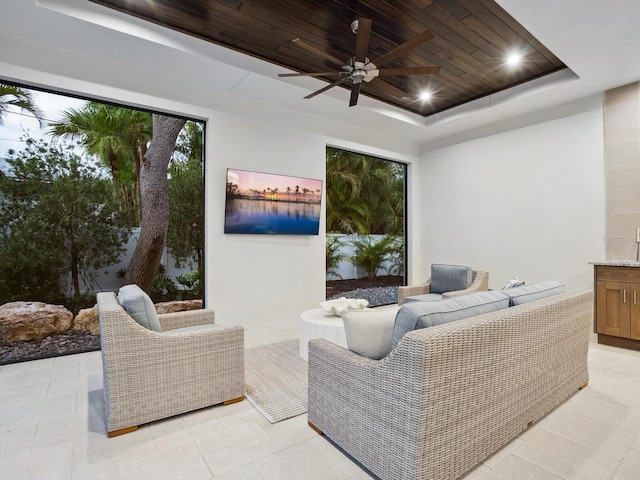 living room featuring ceiling fan, a raised ceiling, and wooden ceiling