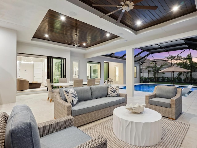 patio terrace at dusk with a lanai, ceiling fan, and an outdoor living space