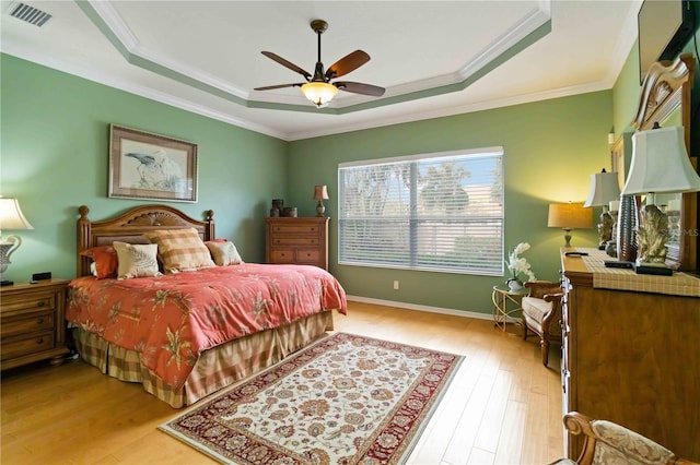 bedroom featuring a raised ceiling, ceiling fan, crown molding, and light hardwood / wood-style floors