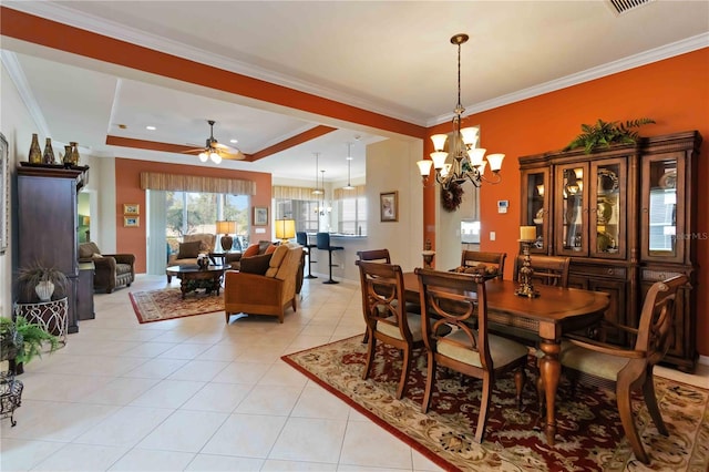 tiled dining area featuring a tray ceiling, crown molding, and ceiling fan with notable chandelier