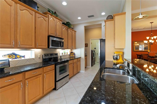 kitchen with pendant lighting, crown molding, sink, appliances with stainless steel finishes, and washing machine and clothes dryer