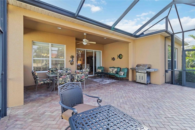 view of patio with ceiling fan, area for grilling, an outdoor living space, and glass enclosure