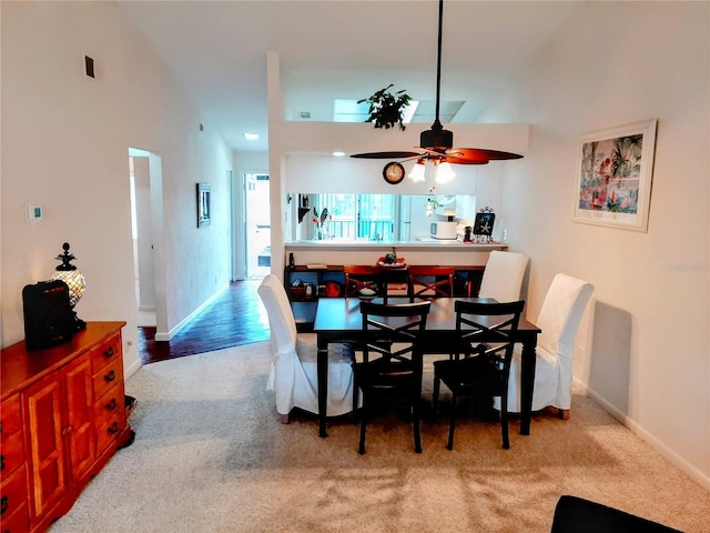 carpeted dining area with high vaulted ceiling and ceiling fan