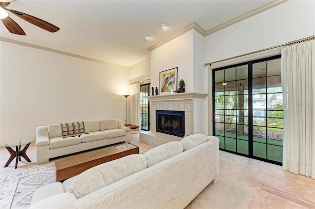 living room with crown molding, a textured ceiling, light carpet, a tiled fireplace, and ceiling fan