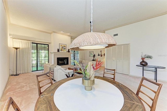 dining room featuring a tiled fireplace, a textured ceiling, light carpet, and ornamental molding