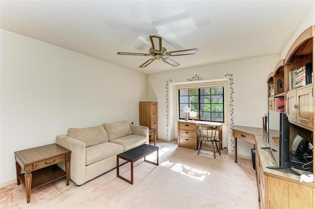 interior space with a textured ceiling, light carpet, and ceiling fan