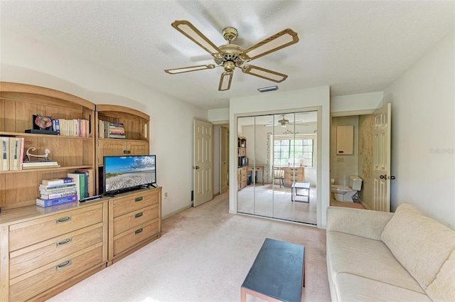 living room with a textured ceiling, light carpet, and ceiling fan