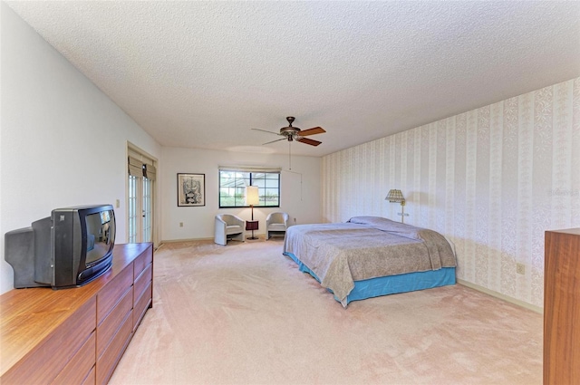 bedroom featuring a textured ceiling, light colored carpet, and ceiling fan