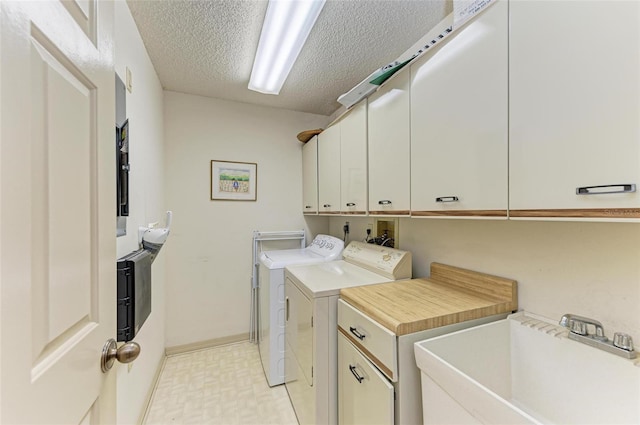 washroom with cabinets, sink, washer and dryer, and a textured ceiling