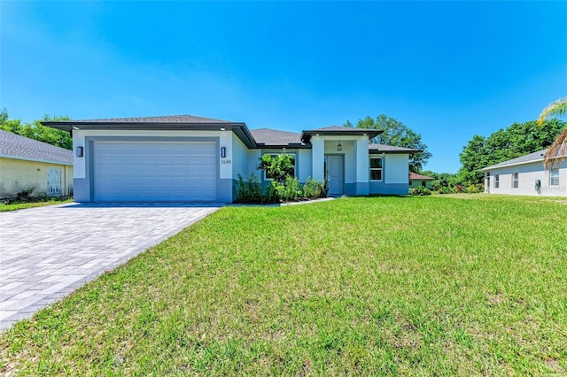 7648 Totem Ave, North Port, FL 34291 - prairie-style home featuring stucco siding, a garage, decorative driveway, and a front lawn