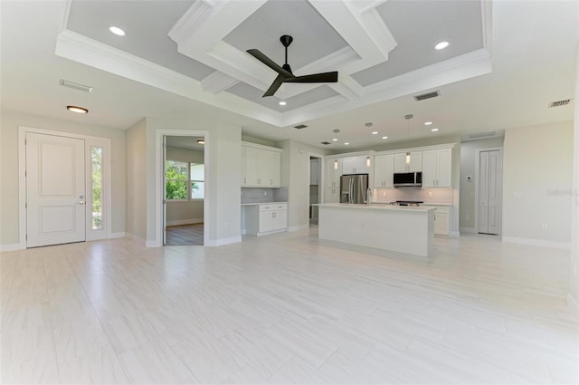 unfurnished living room with ornamental molding, coffered ceiling, sink, a tray ceiling, and ceiling fan