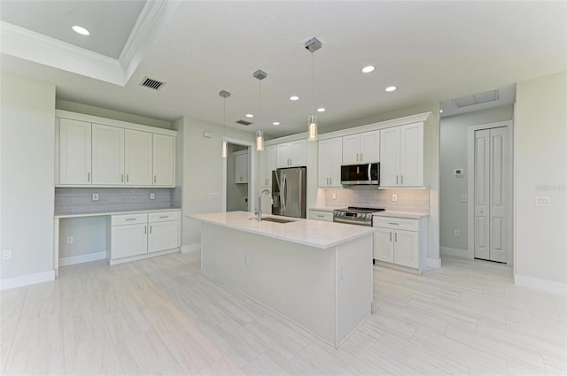 kitchen with stainless steel appliances, white cabinetry, an island with sink, and decorative light fixtures