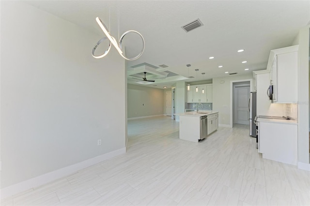 kitchen with stainless steel appliances, a center island with sink, tasteful backsplash, pendant lighting, and white cabinetry