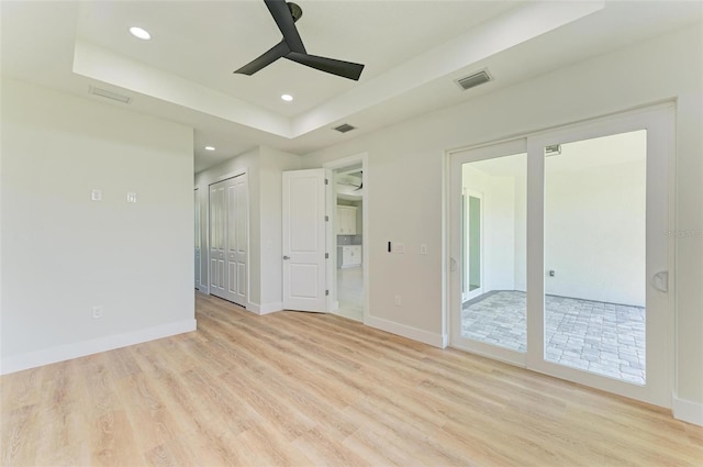 interior space featuring access to outside, a raised ceiling, ceiling fan, and light hardwood / wood-style flooring