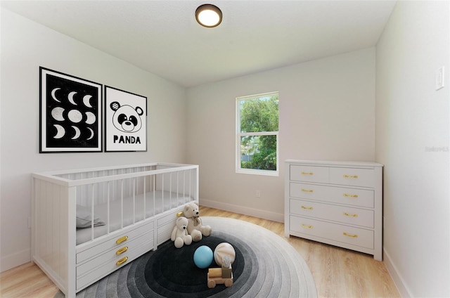 bedroom featuring a crib and light hardwood / wood-style floors