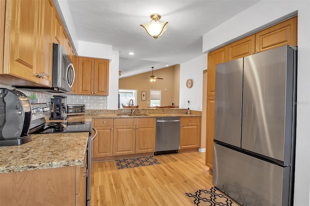 kitchen featuring lofted ceiling, sink, stainless steel appliances, tasteful backsplash, and light hardwood / wood-style floors