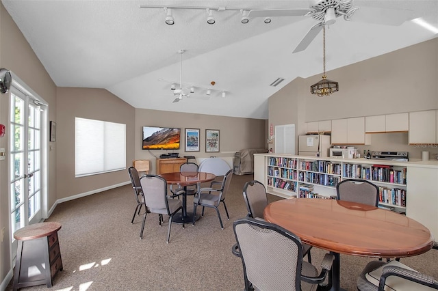 carpeted dining room featuring vaulted ceiling, ceiling fan, and track lighting