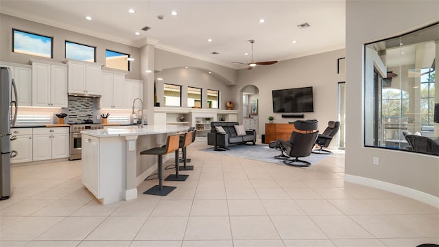 kitchen featuring appliances with stainless steel finishes, light stone counters, a healthy amount of sunlight, and an island with sink