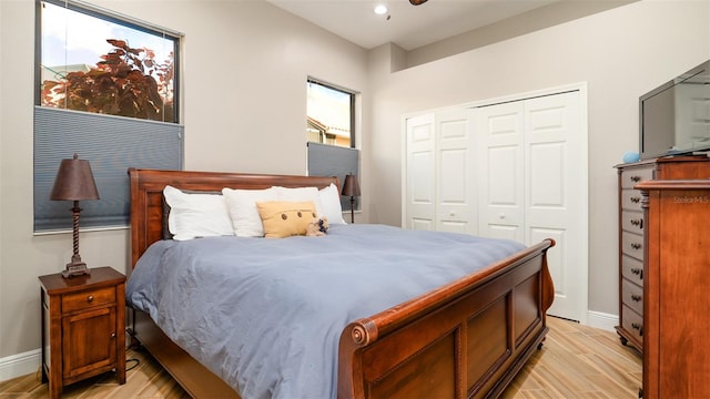 bedroom featuring light hardwood / wood-style floors, multiple windows, and a closet