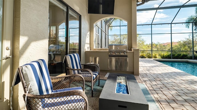 view of patio featuring a lanai, a grill, exterior kitchen, and an outdoor fire pit