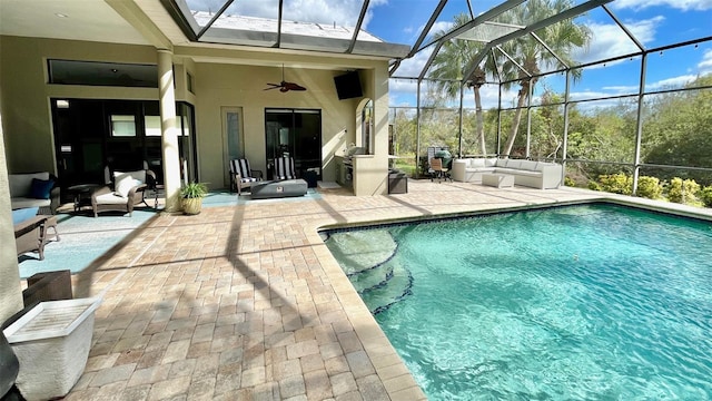 view of pool with an outdoor hangout area, glass enclosure, ceiling fan, and a patio area