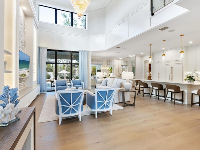 living room featuring light hardwood / wood-style flooring, a high ceiling, and an inviting chandelier