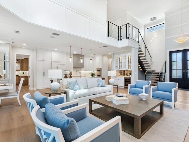 living room with french doors, beverage cooler, a high ceiling, and light wood-type flooring