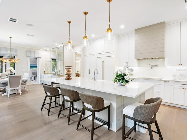 kitchen with white cabinetry, a large island, pendant lighting, and paneled built in fridge