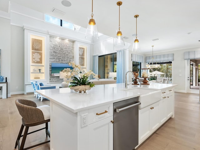 kitchen featuring a center island with sink, white cabinets, sink, stainless steel dishwasher, and decorative light fixtures