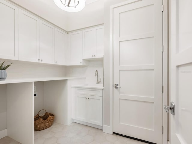 washroom with electric dryer hookup, sink, light tile patterned floors, and cabinets