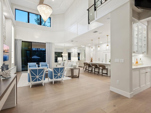 living room featuring a notable chandelier, a high ceiling, and light hardwood / wood-style flooring