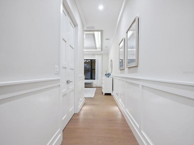 hallway with crown molding and light hardwood / wood-style flooring