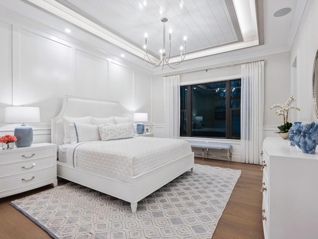 bedroom featuring hardwood / wood-style floors, a notable chandelier, crown molding, and a tray ceiling