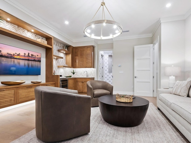 living room with crown molding, light hardwood / wood-style flooring, beverage cooler, and sink