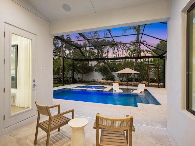 pool at dusk with a patio area, a lanai, and an in ground hot tub