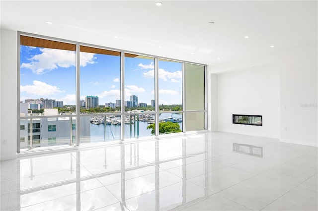 empty room with expansive windows, a water view, and light tile patterned floors