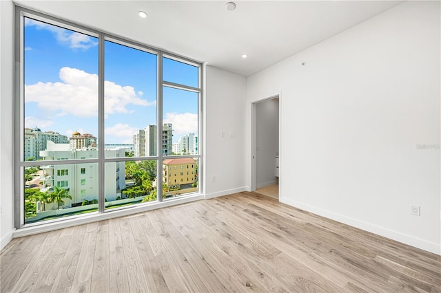 unfurnished room featuring floor to ceiling windows and light hardwood / wood-style flooring