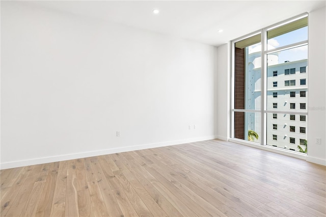 spare room featuring light hardwood / wood-style flooring and a wall of windows