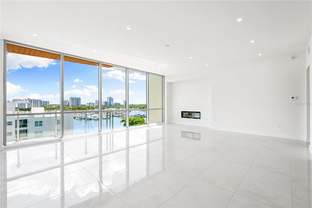 tiled empty room featuring a wall of windows and a water view