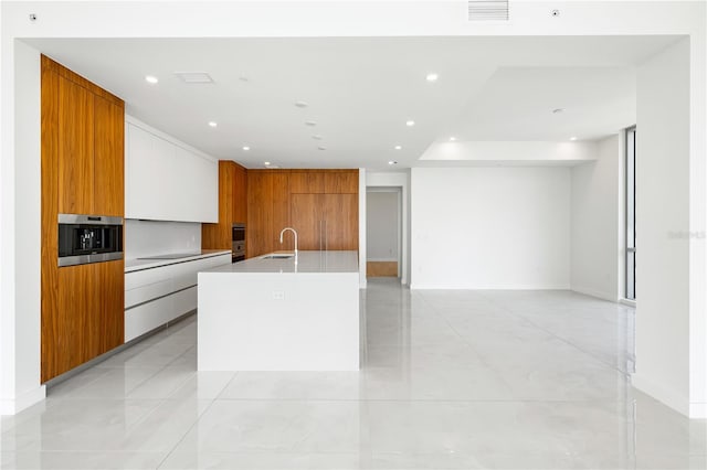 kitchen featuring white cabinetry, sink, light tile patterned floors, and a spacious island