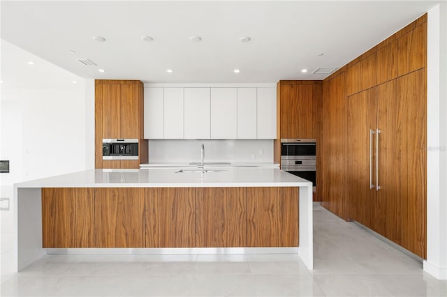 kitchen featuring sink, white cabinets, double oven, and a spacious island