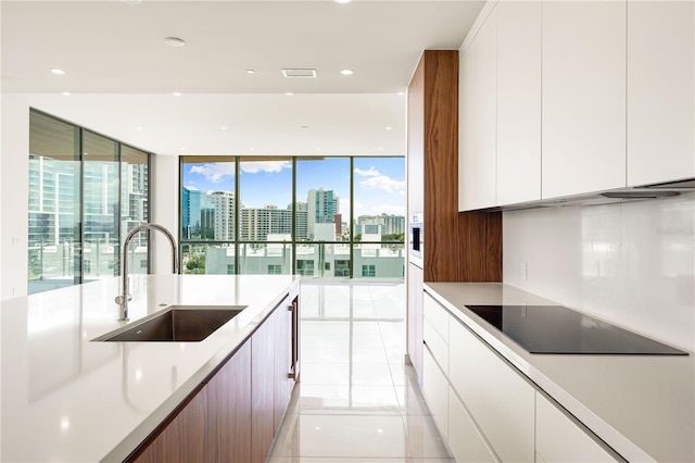 kitchen with black electric cooktop, sink, floor to ceiling windows, and light tile patterned flooring