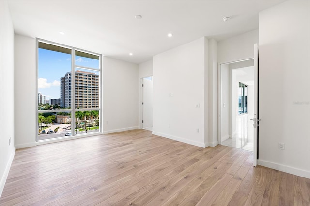 empty room with floor to ceiling windows and light wood-type flooring