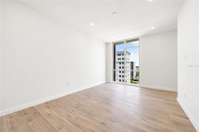 spare room with expansive windows and light wood-type flooring