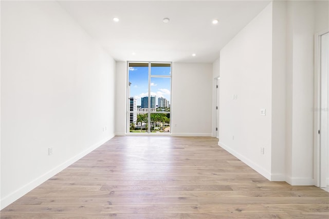 unfurnished room with light hardwood / wood-style flooring and floor to ceiling windows