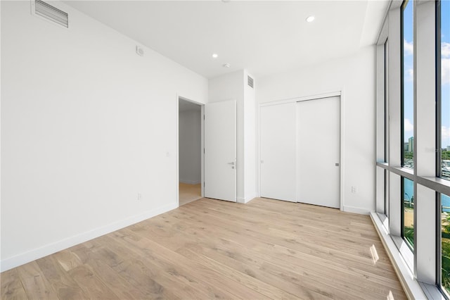 unfurnished bedroom with a closet, light hardwood / wood-style floors, and floor to ceiling windows