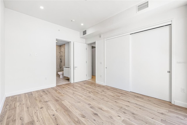 unfurnished bedroom with connected bathroom, a closet, and light wood-type flooring