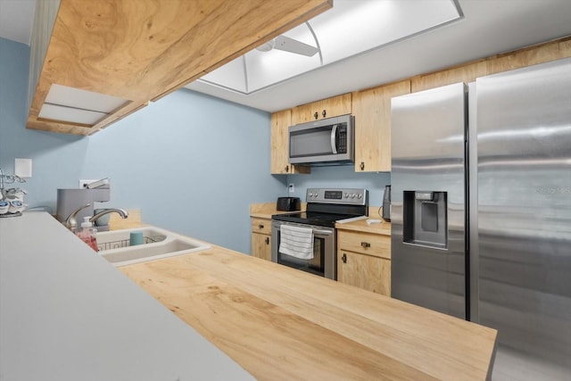 kitchen with light brown cabinets, appliances with stainless steel finishes, sink, and wood counters